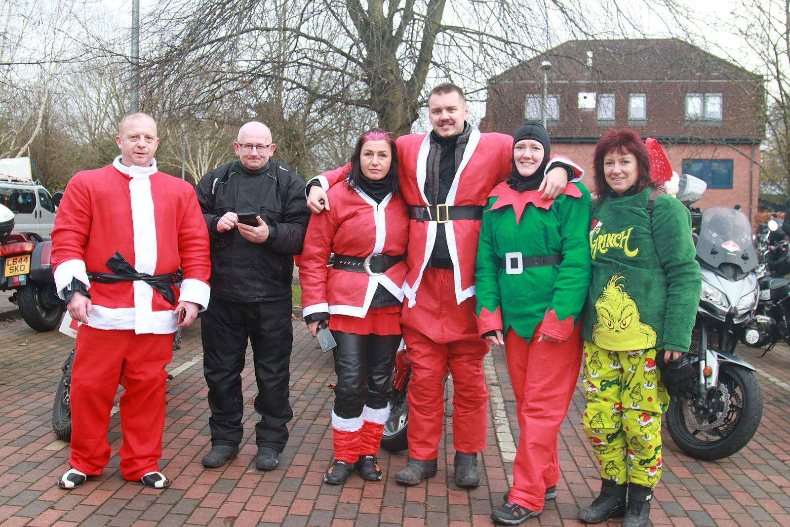 People dressed as Santa Claus and elves, posing together and spreading holiday cheer