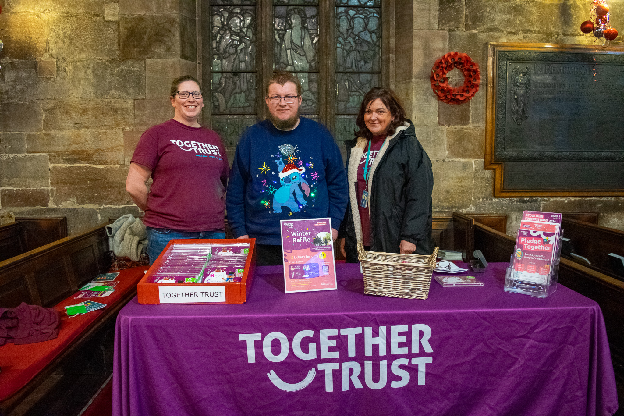 Two ladies and a man at the Together Trust stall, happily selling Christmas cards and collecting donations during the event