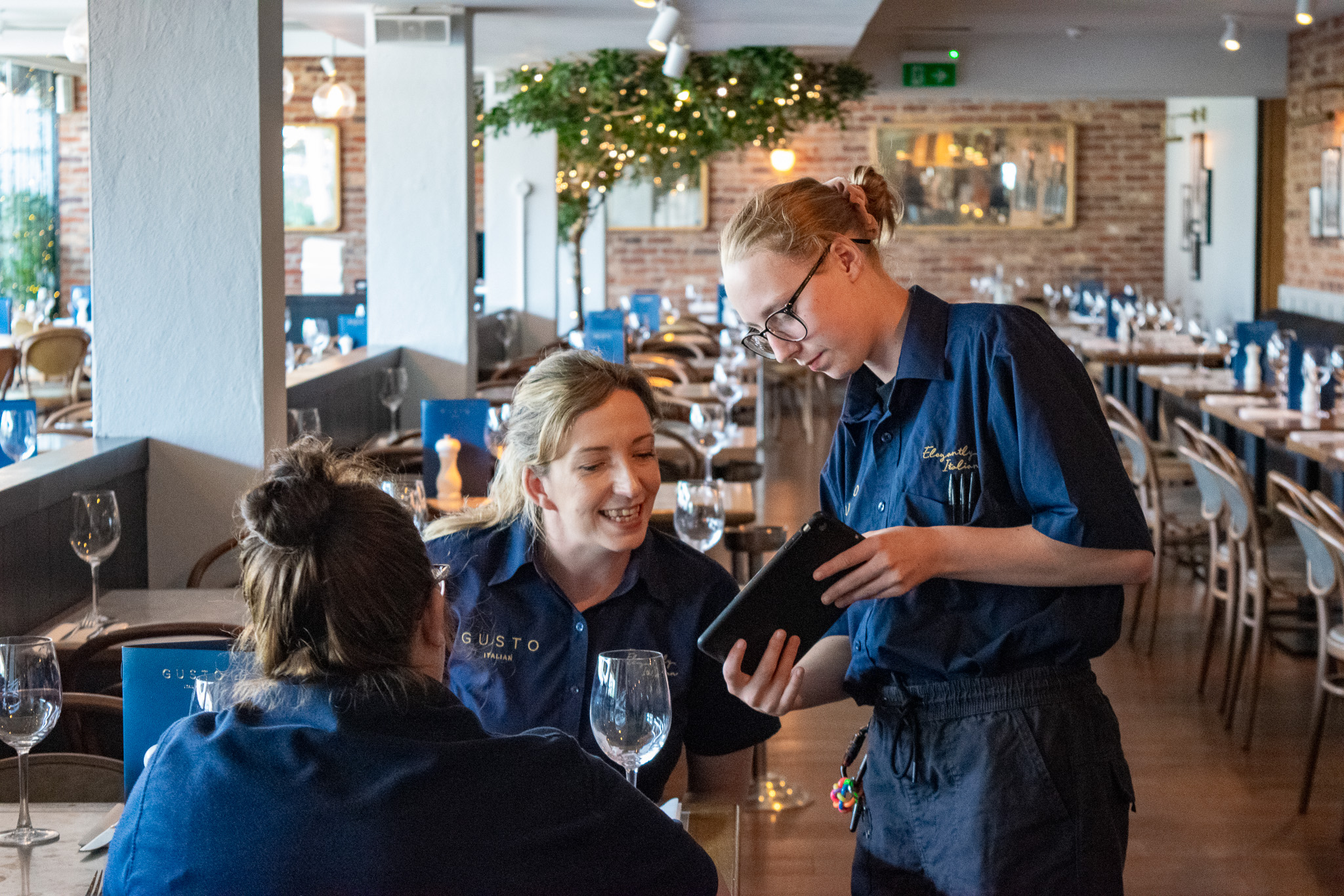 Teenage girl wearing uniform working on a tablet with Gusto Staff.