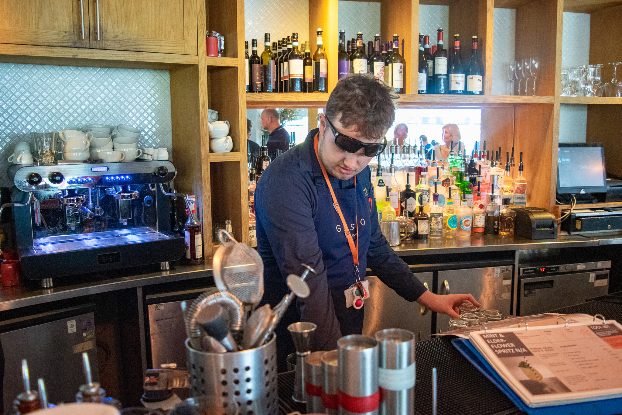 Teenage boy wearing uniform and sunglasses working at the restaurant bar. 