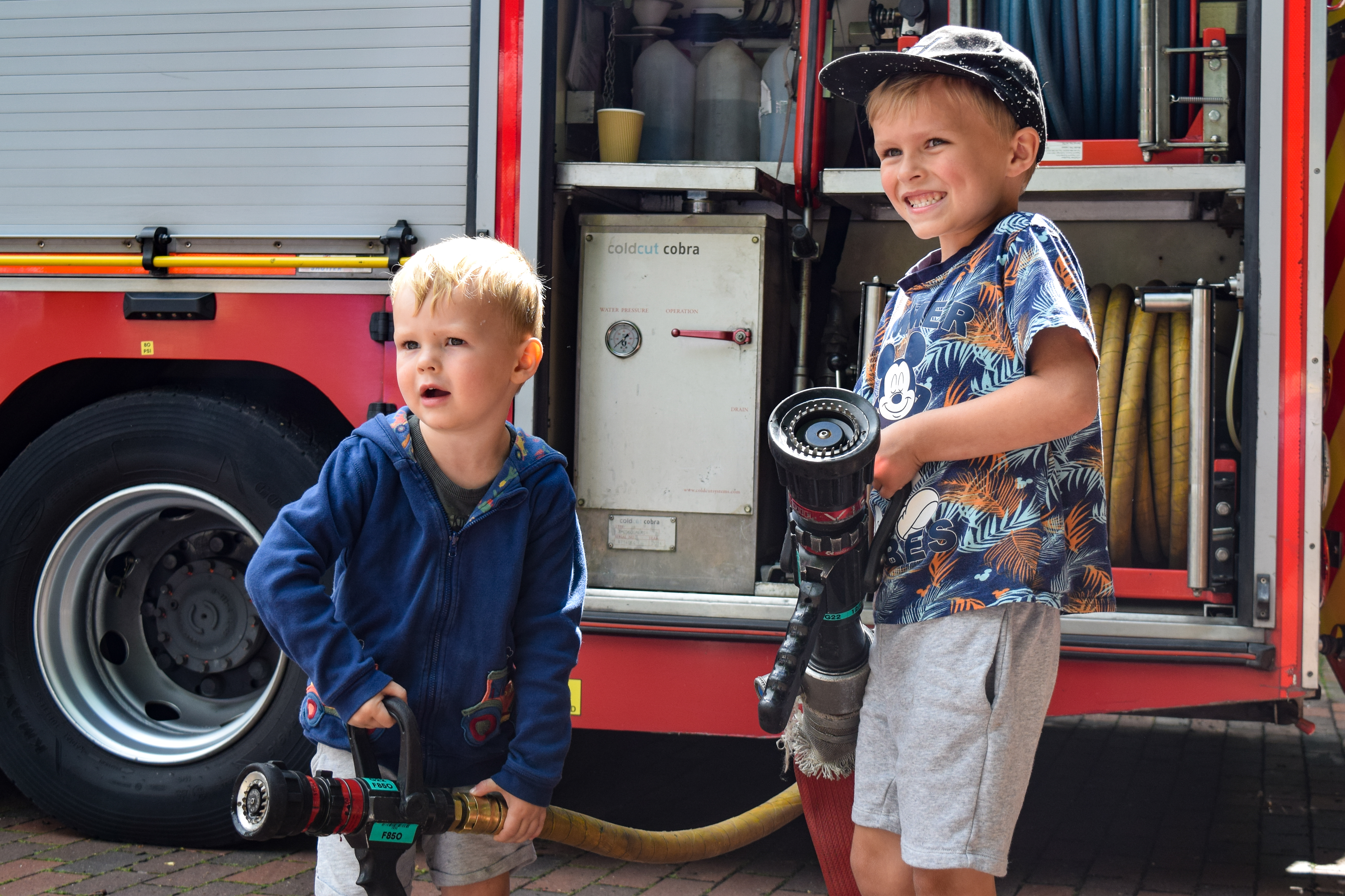 Two young boys smiling and exploring the fire engine.