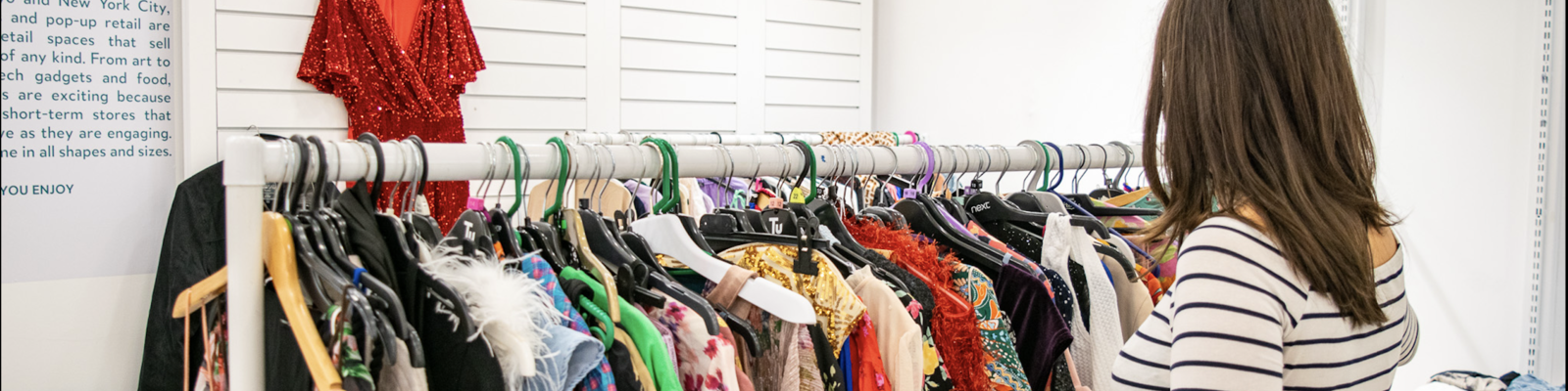 a woman looking through a rail of clothes