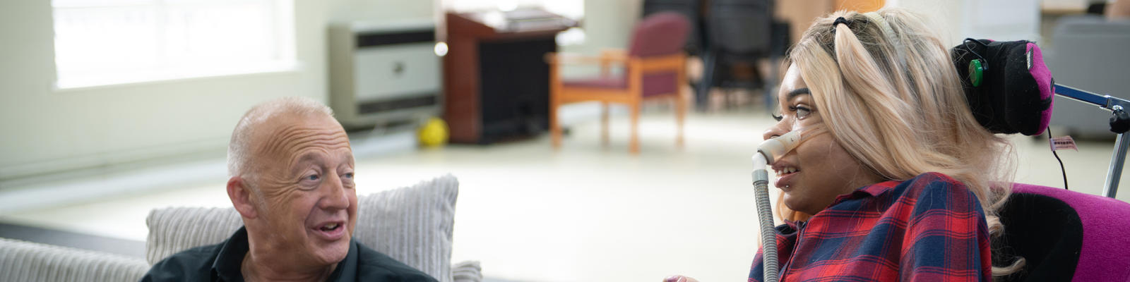 An older man talking to a young woman in a wheelchair 