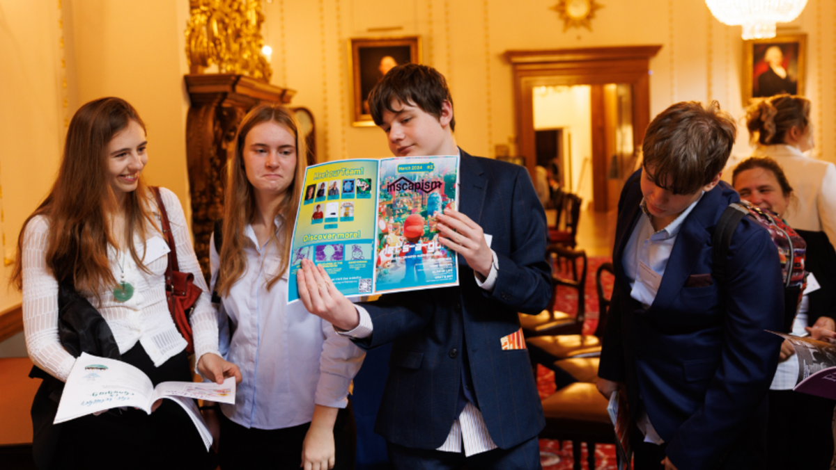 A student from Inscape showing his peers the INscapism magazine at an awards ceremony