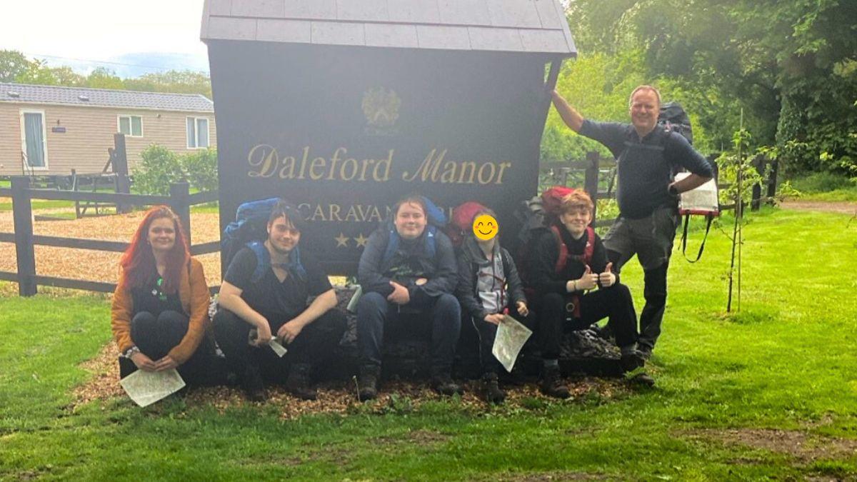 A group of students with staff members in front of the sign of Daleford Manor in Cheshire Country Park.