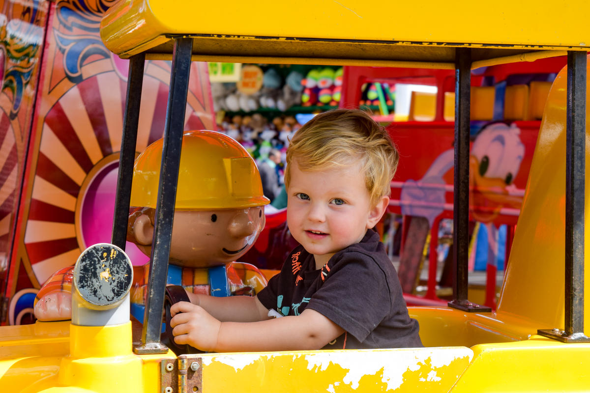 A child looking at the camera and enjoying one of the festival's rides.