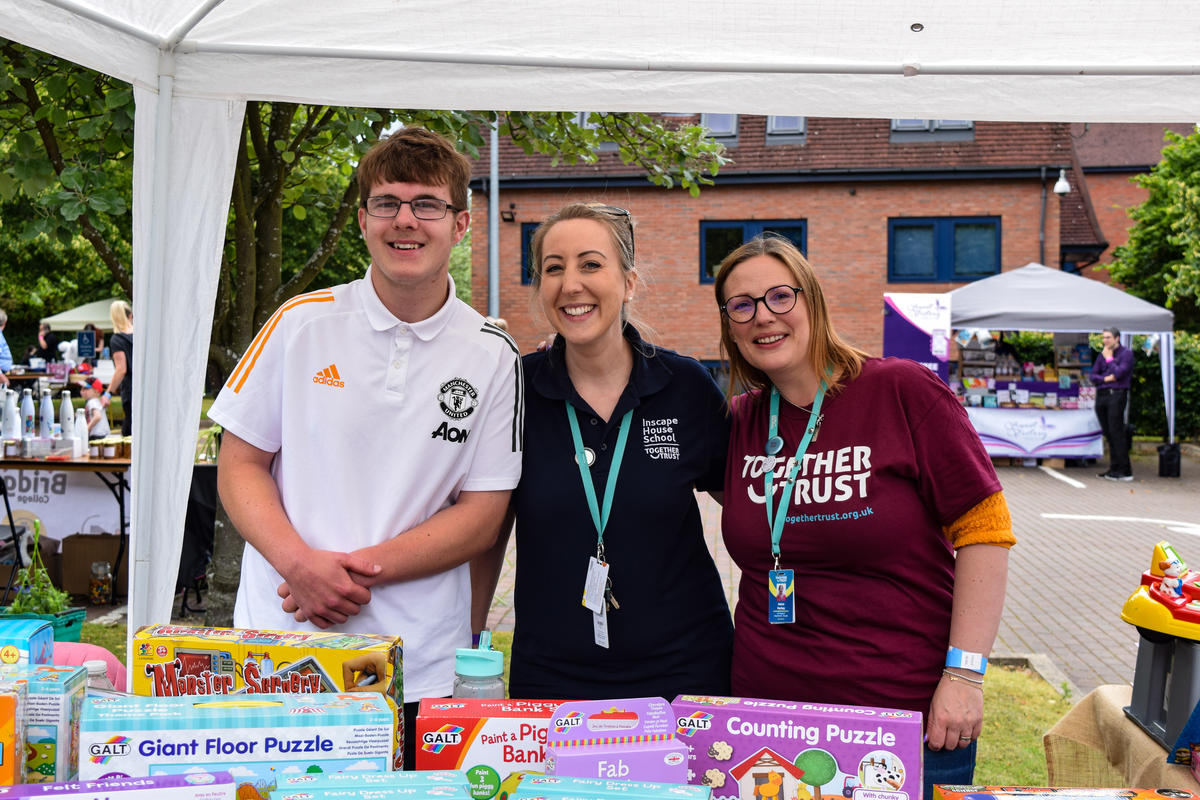 three people smiling stood at a stall