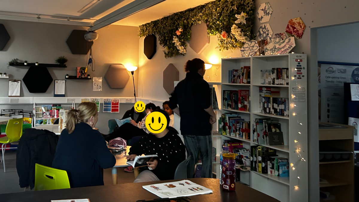 A photo showing the Bridge College library in the cafe. Students are sat at tables and on sofa's reading books