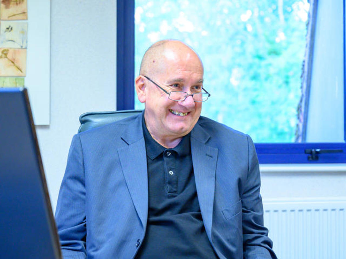 Mark sat at the Together Trust office, smiling.