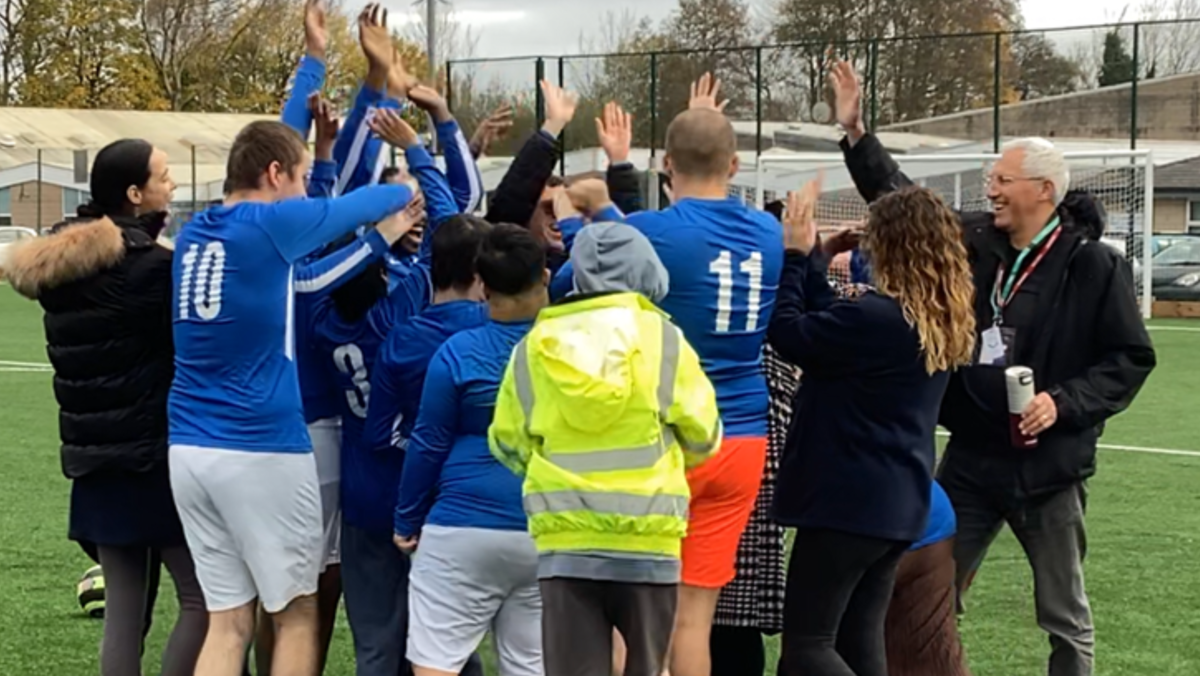 The Bridge football team in a huddle giving each other a high-five