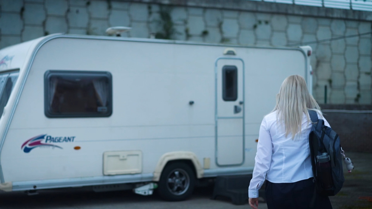 Care leaver in school uniform walking towards a caravan.