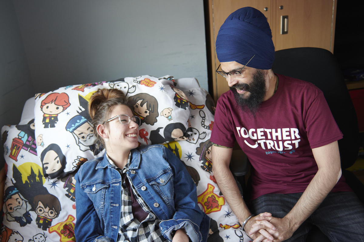 two people smiling at each other, one is wearing a purple together trust branded t shirt