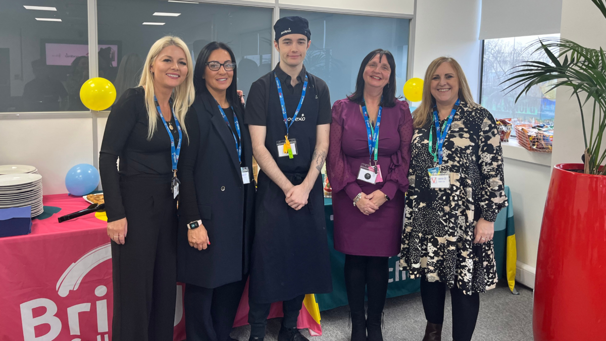 A photograph of the Sodexo and Bridge College team standing in front of tables.