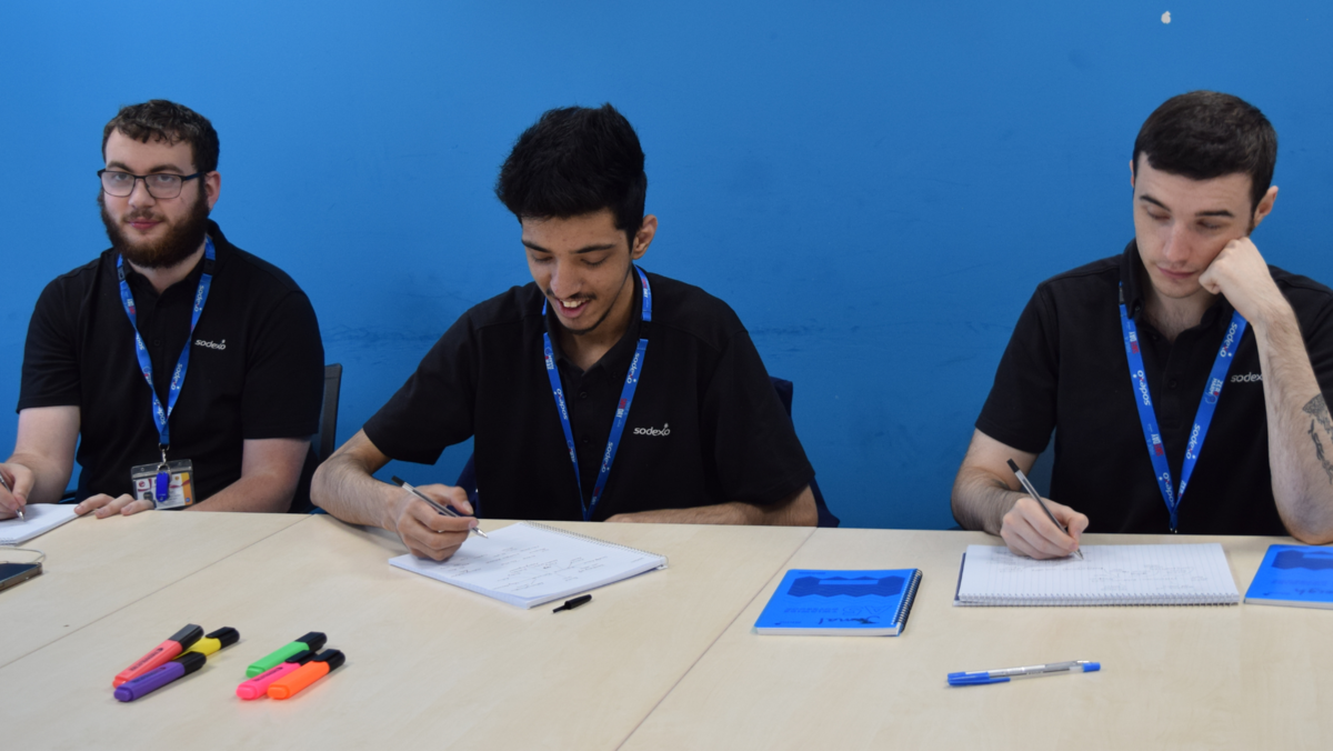 Three students sat at a table busy writing