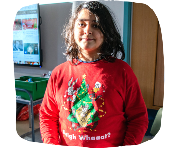 Student wearing a red christmas jumper with Looney Toons characters that reads "Sleigh what?" 