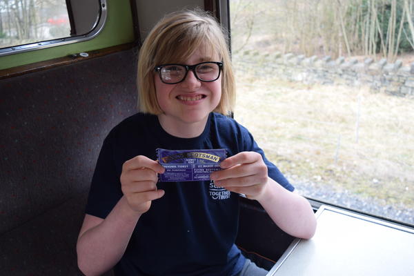  a young boy smiling holding a train ticket
