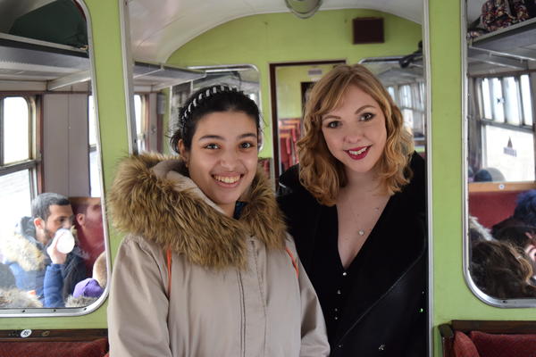 two women smiling at the camera on board a train