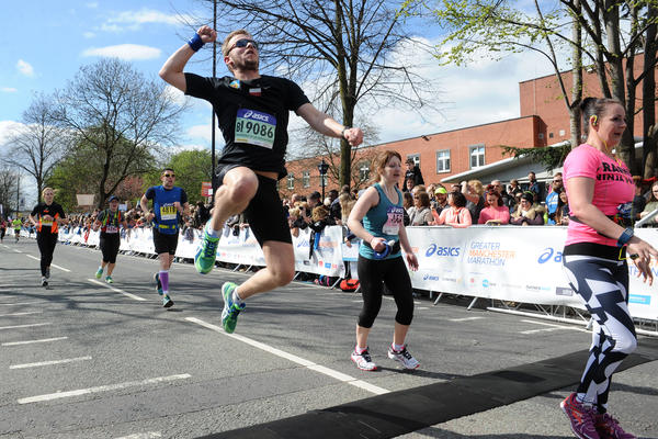 a man punching the air as he crosses the finish line of the Manchester Marathon