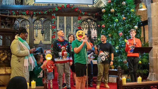 Students and staff on stage, all dressed in festive jumpers during a performance