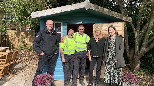 Captured in this image is the dedicated team from Manchester Airport along with staff from the Together Trust, standing proudly in front of the summerhouse.